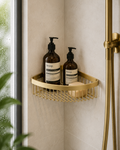 Gold corner shower caddy with Aesop bottles in a bathroom setting