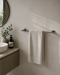 Bathroom setting with a towel hanging on a rack, a plant, and a bottle.