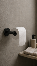 Black toilet paper holder with a roll of toilet paper on a textured wall, next to a sink with a towel and soap dispenser.