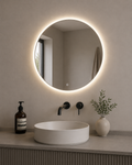 Bathroom vanity with round illuminated mirror, sink, and decorative elements.